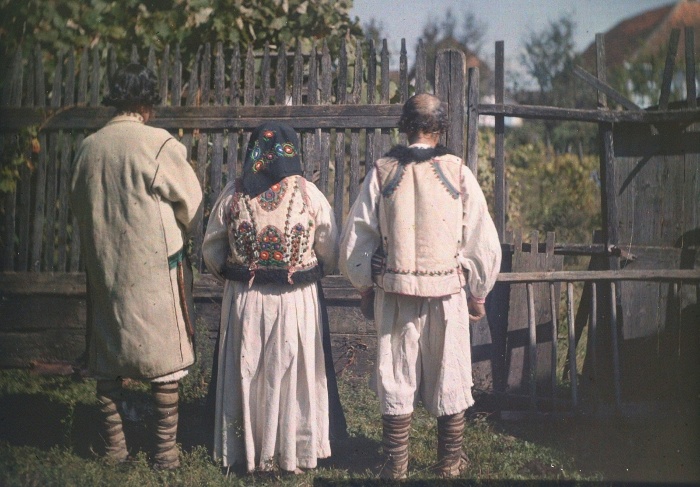 Román férfiak bocskorban és szűrujjasban, román nő bőrmellényben, Tatárfalván, Románia, 1911. Színes, autokróm üveglemez, 13x18 centiméter  (GYÖRFFY ISTVÁN FELVÉTELE, NÉPRAJZI MÚZEUM)