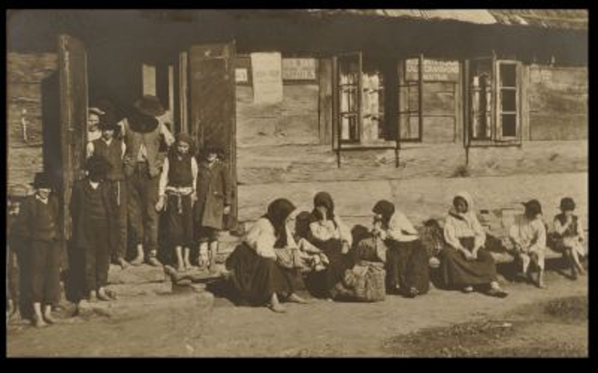 Adler italmérés boltja, ajtajában zsidó férfi és fiúk kalapban, cicittel Alsóapsa, 1911. Balogh Péter felvétele